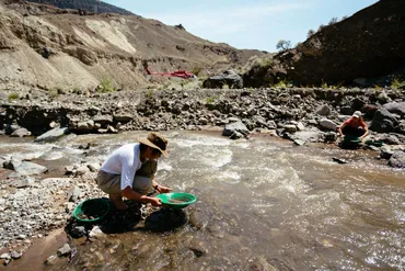 Gold panning in lone cabin creek with helicopter waiting nearby