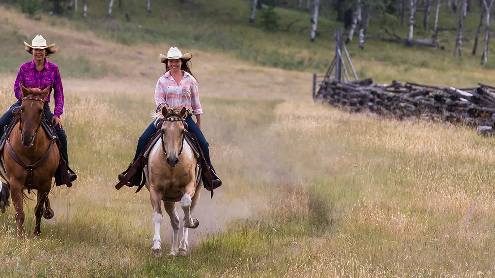 Mother and daughter cowgirls going for a gallop in the meadow at Siwash Lake