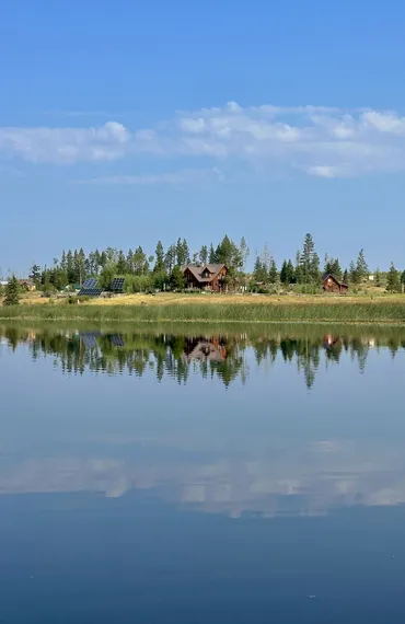 The main lodge and barn overlook Siwash Lake on a calm summer day